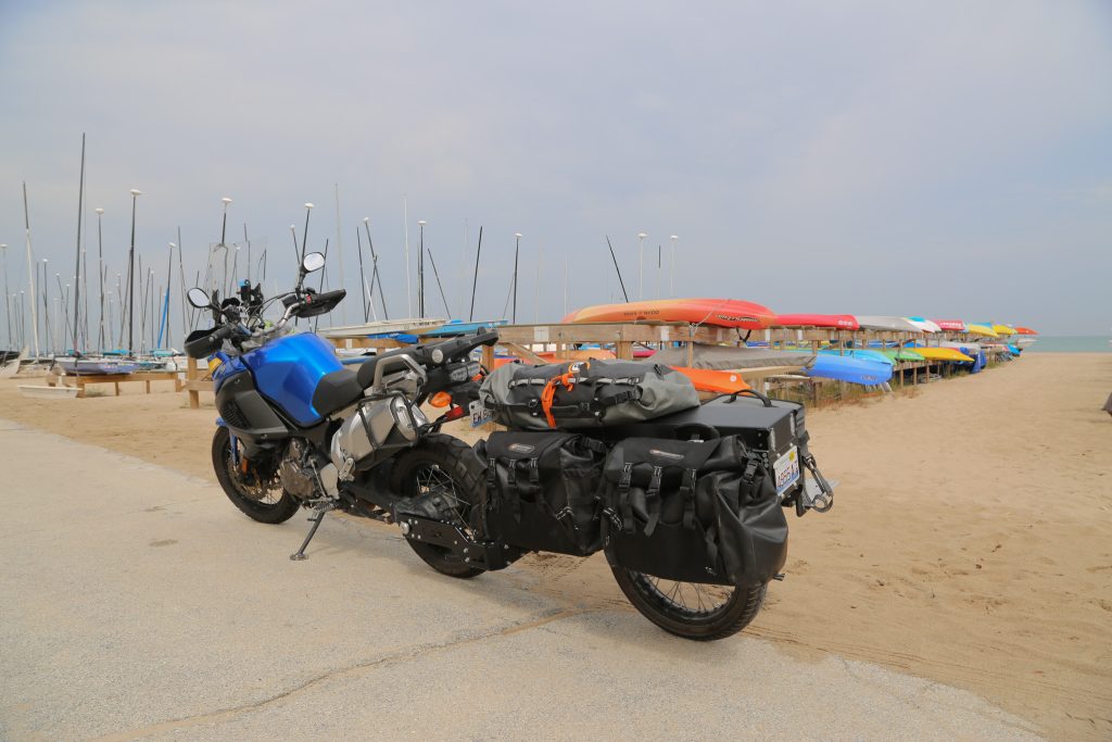 The Pasq ADV1 moto trailer near the beach and colorful boats.